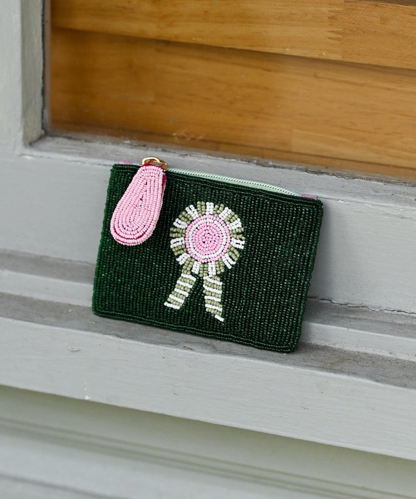 Green clutch with beads on a wooden surface. Features Tucker Tweed's signature equestrian style