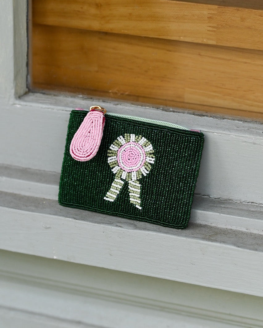 Green clutch with beads on a wooden surface. Features Tucker Tweed's signature equestrian style