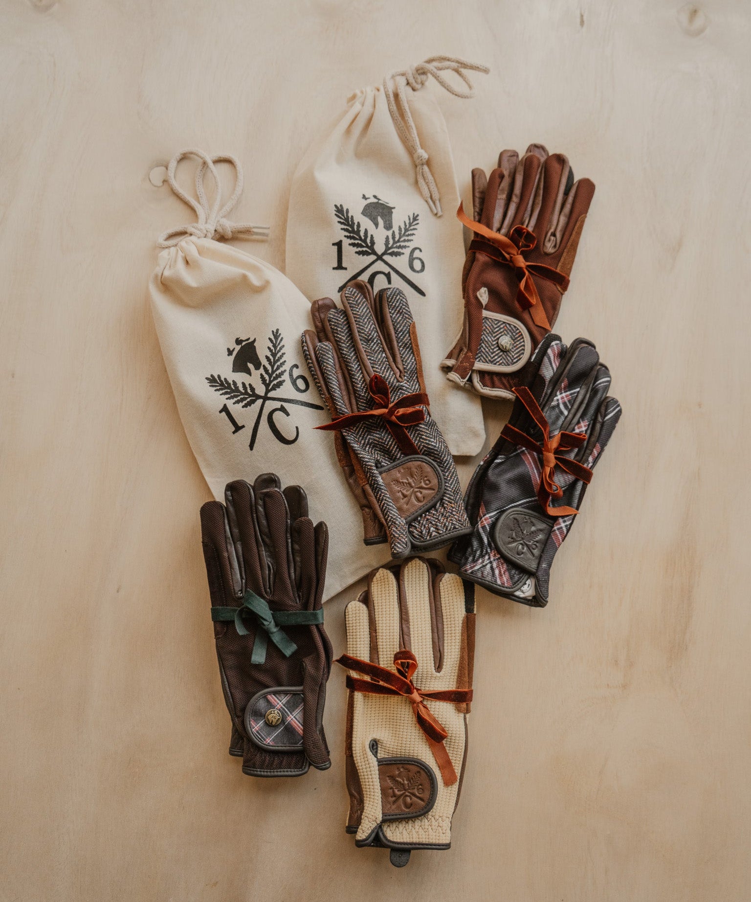 Pairs of leather gloves with drawstring bags on a wooden surface